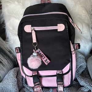 Pink and black book bag with fluffy ball bunny chain and a love chain .
